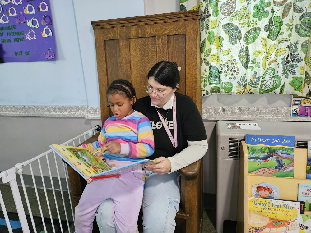 Teacher reading with a child in a Brookline Sprouts classroom